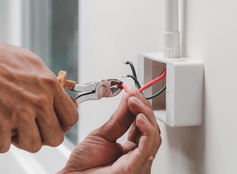 worker with a platinum tool fixing the wires of a white outlet